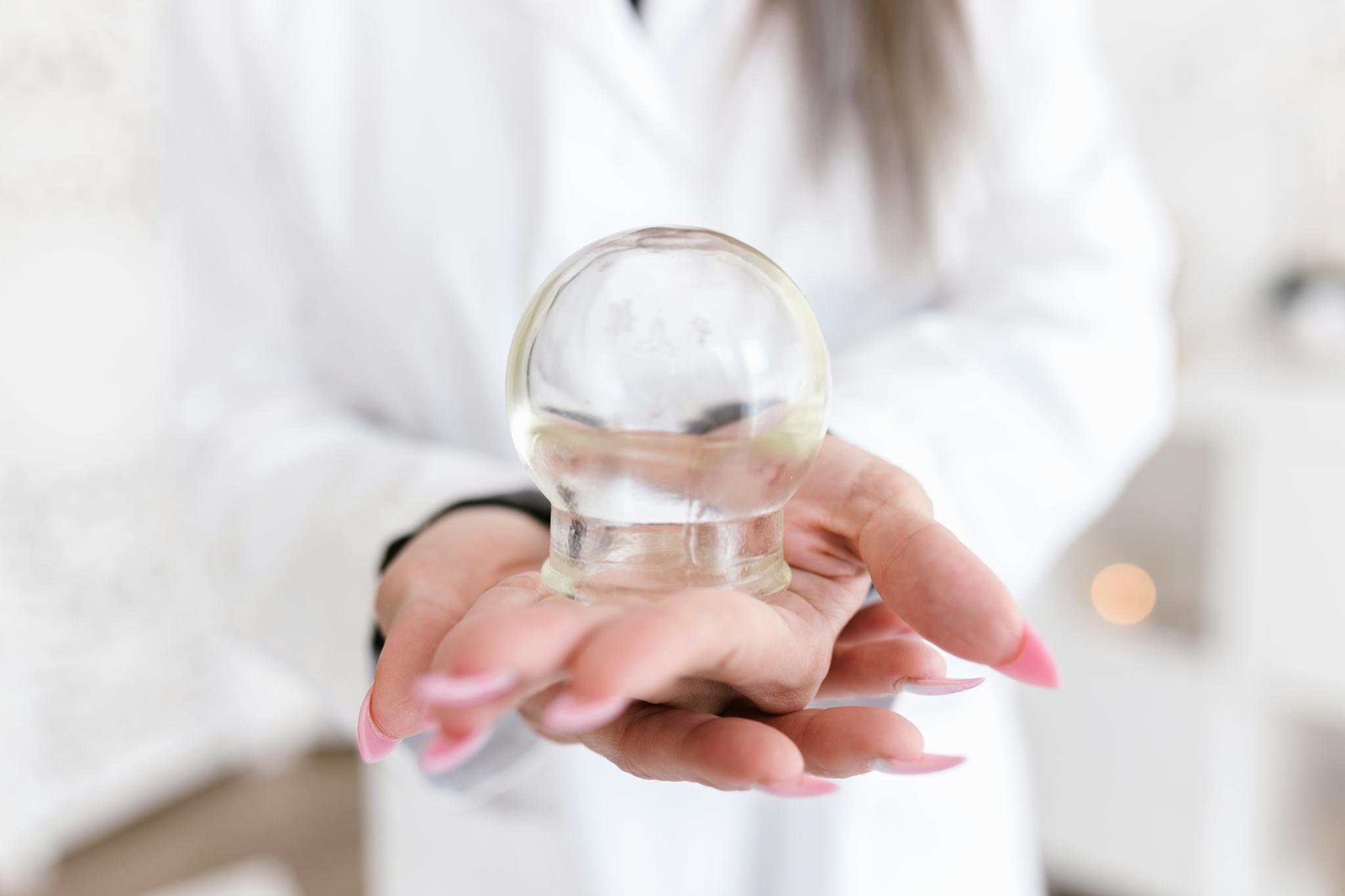A woman holds a glass cupping therapy cup, highlighting alternative medicine practices.